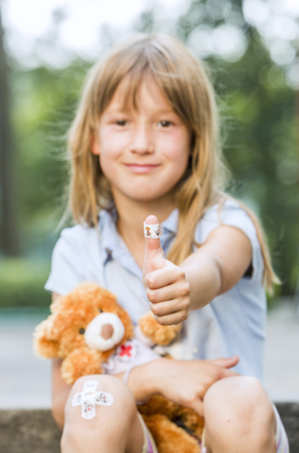 Mädchen mit Teddybär und Pflaster am Daumen