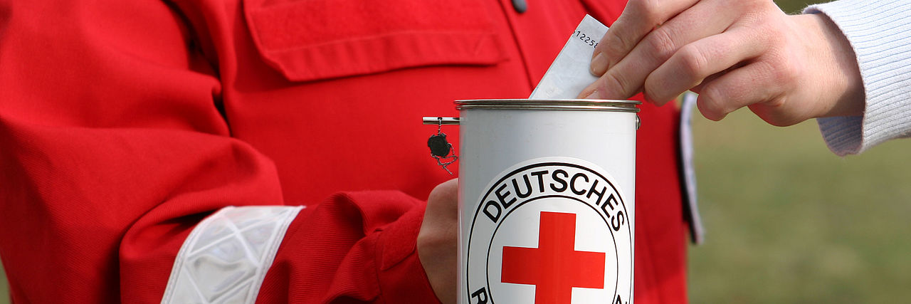 Spender steckt einen Geldschein in eine Spendendose.