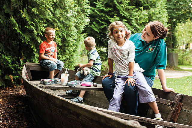 Betreuerin beim Kinderschminken mit Kindern in einem Kahn