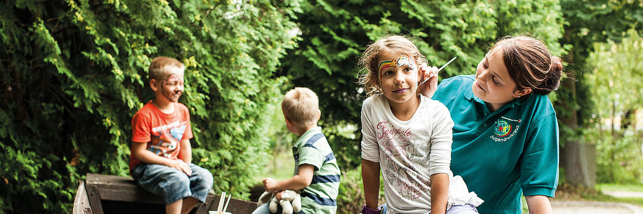 Betreuerin beim Kinderschminken mit Kindern in einem Kahn