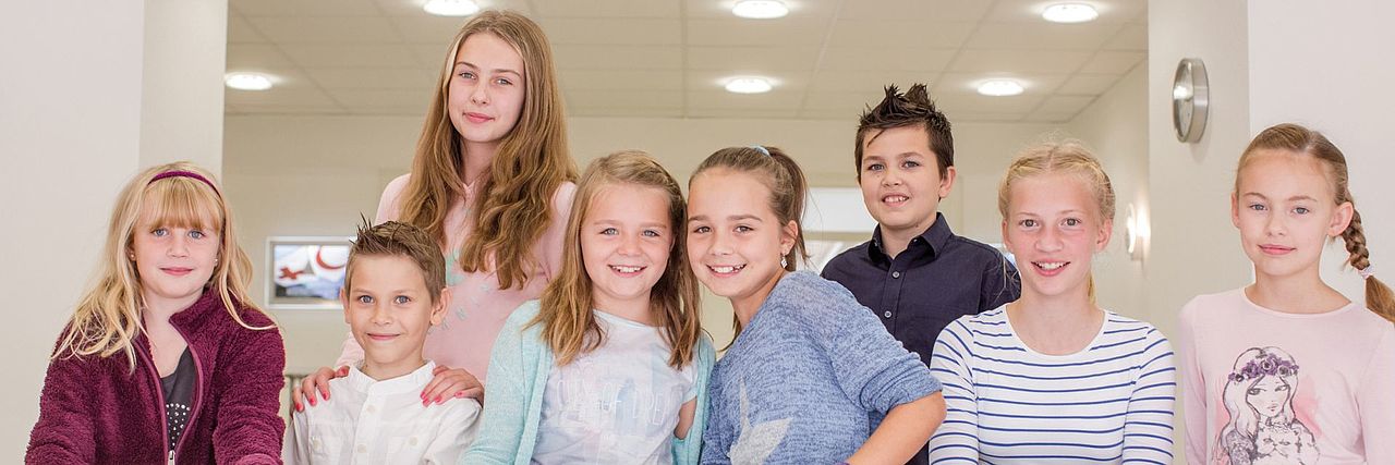 Kinder und Jugend acht Kinder hinter Roll-on-Postern mit Kompaktlogo